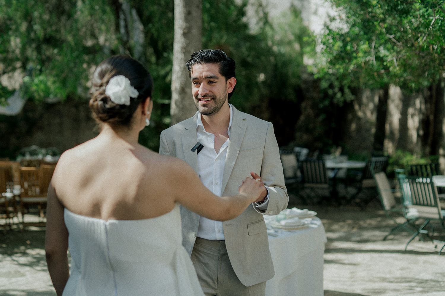 Elegant outdoor wedding scene with tables set among lush greenery and trees.