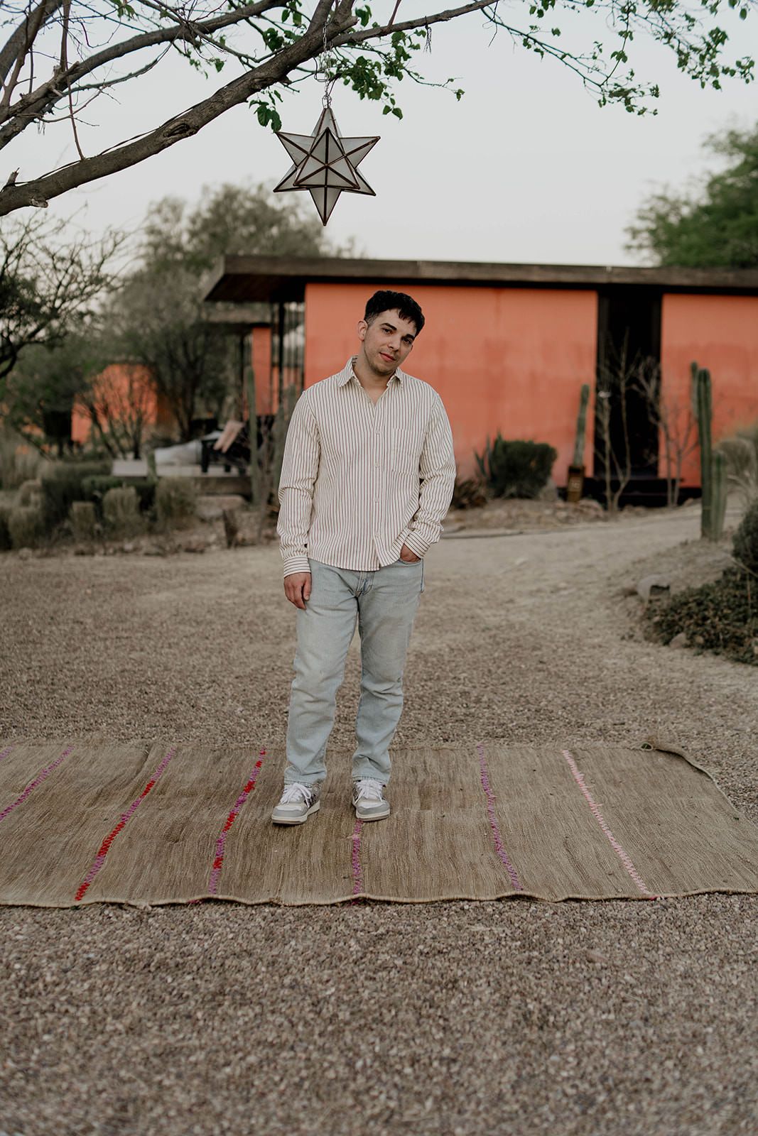 Person in casual attire standing on wooden deck with desert buildings in background.