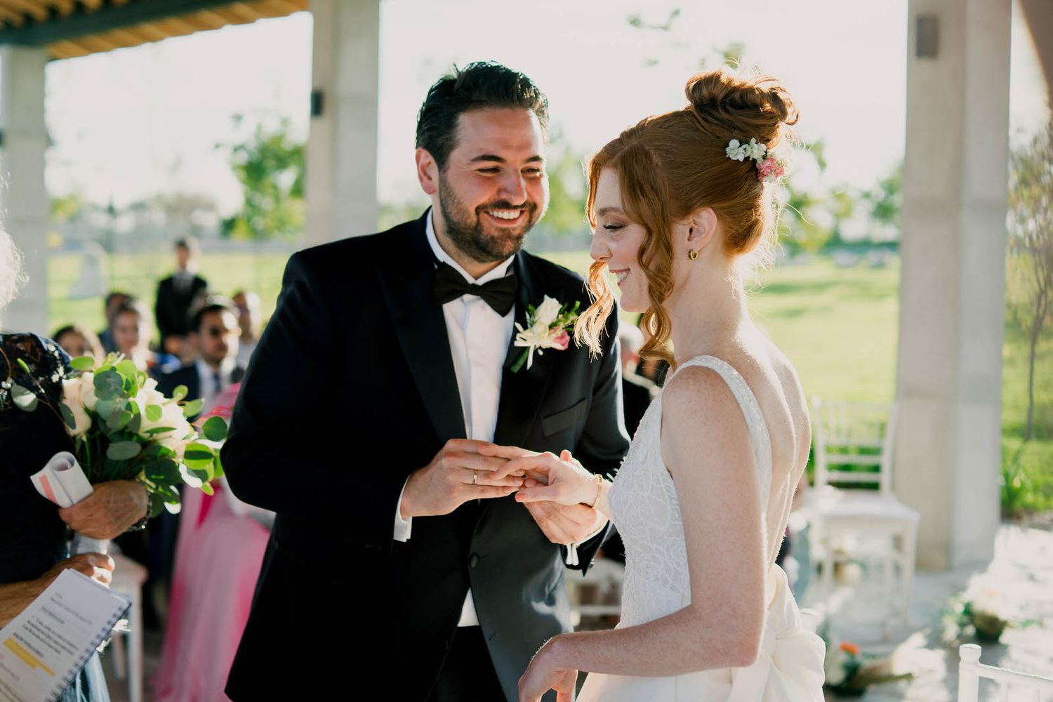 A joyful wedding ceremony moment as newlyweds share a laugh together under an outdoor pavilion.