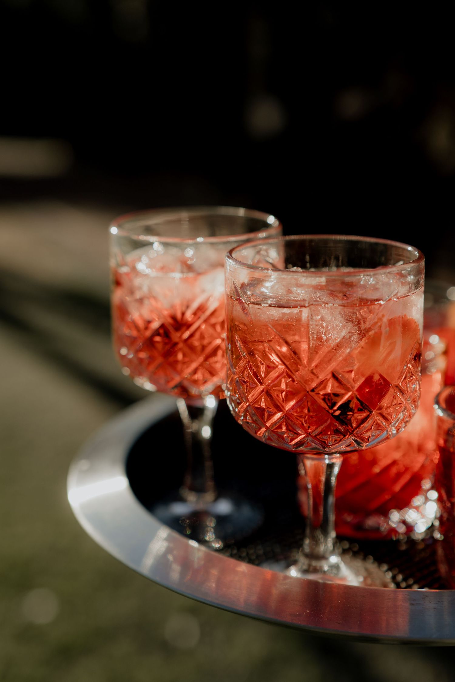 Crystal coupe glasses filled with pink cocktails on a reflective surface.