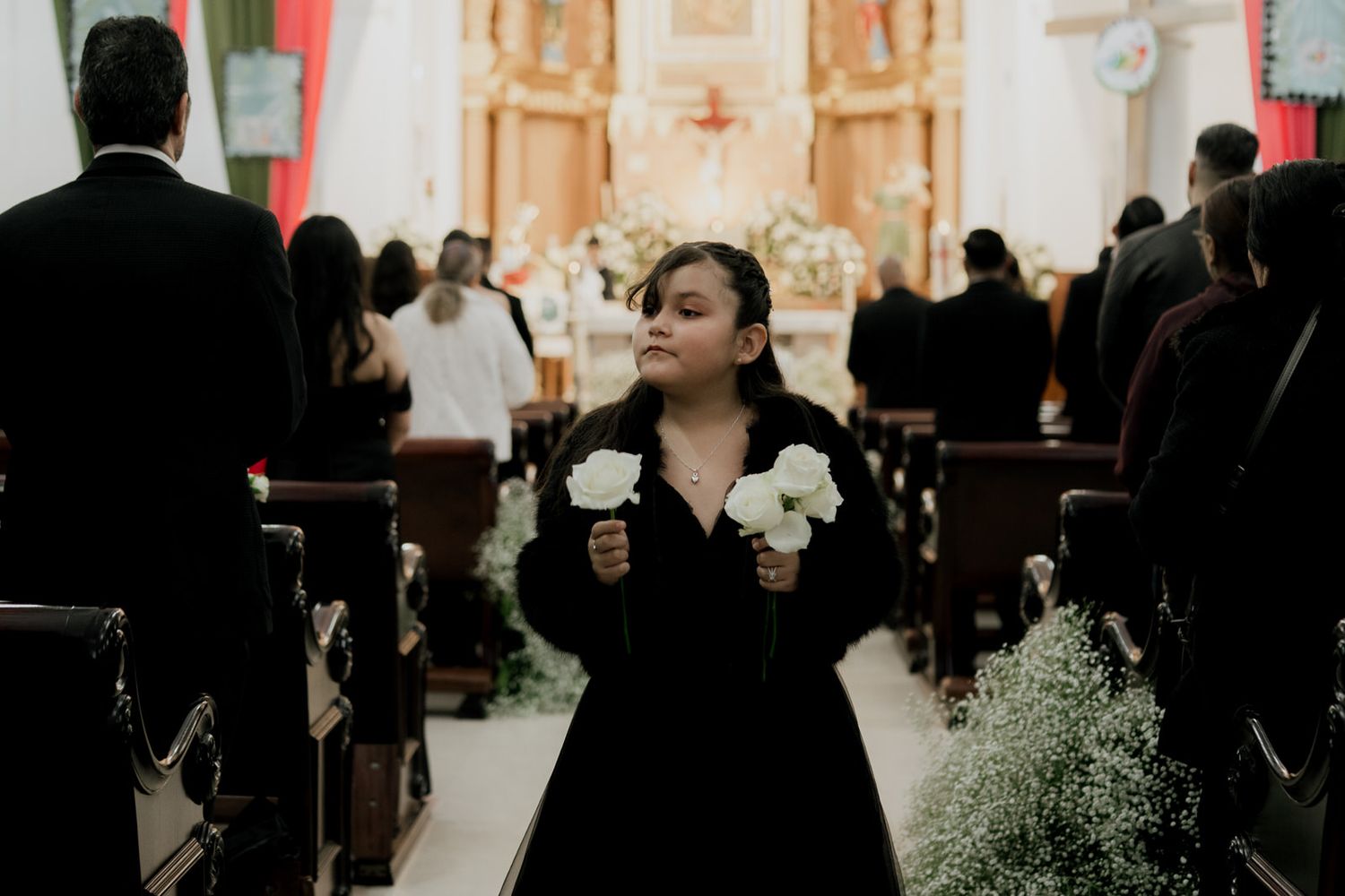 Wedding guests gather in an ornate church interior with decorative lighting.