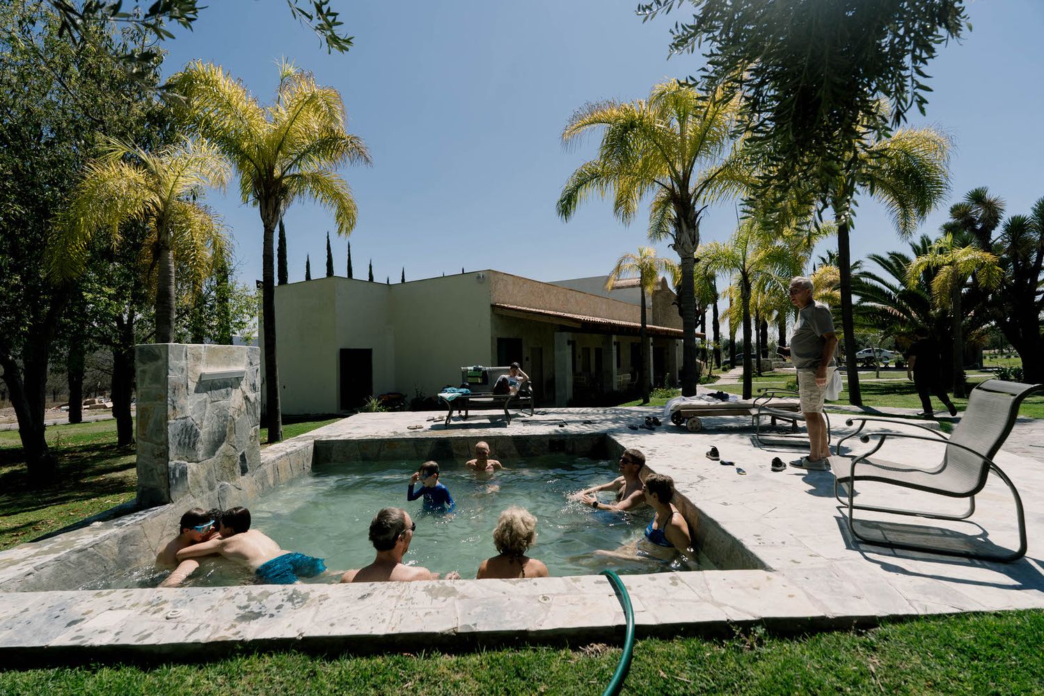 Modern pool area with palm trees and lounge chairs surrounded by landscaped grounds.