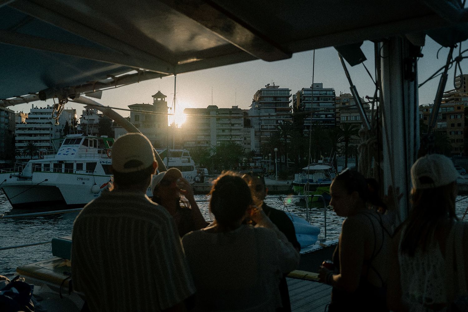 A series of sunset photos showing boats docked at a marina with buildings silhouetted against an orange sky.