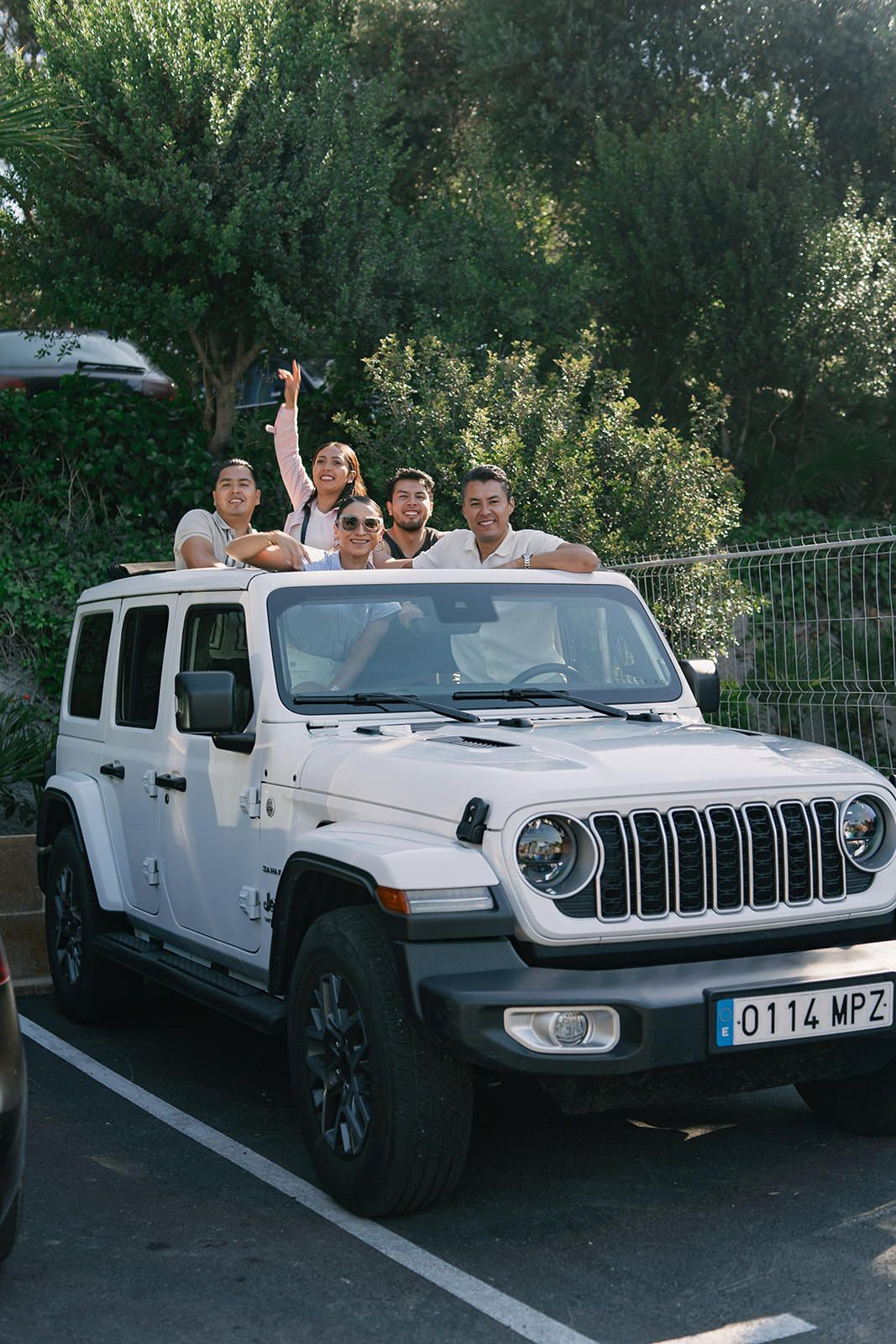 A group of white Jeep Gladiator pickup trucks parked in a row with people gathered around them outdoors.