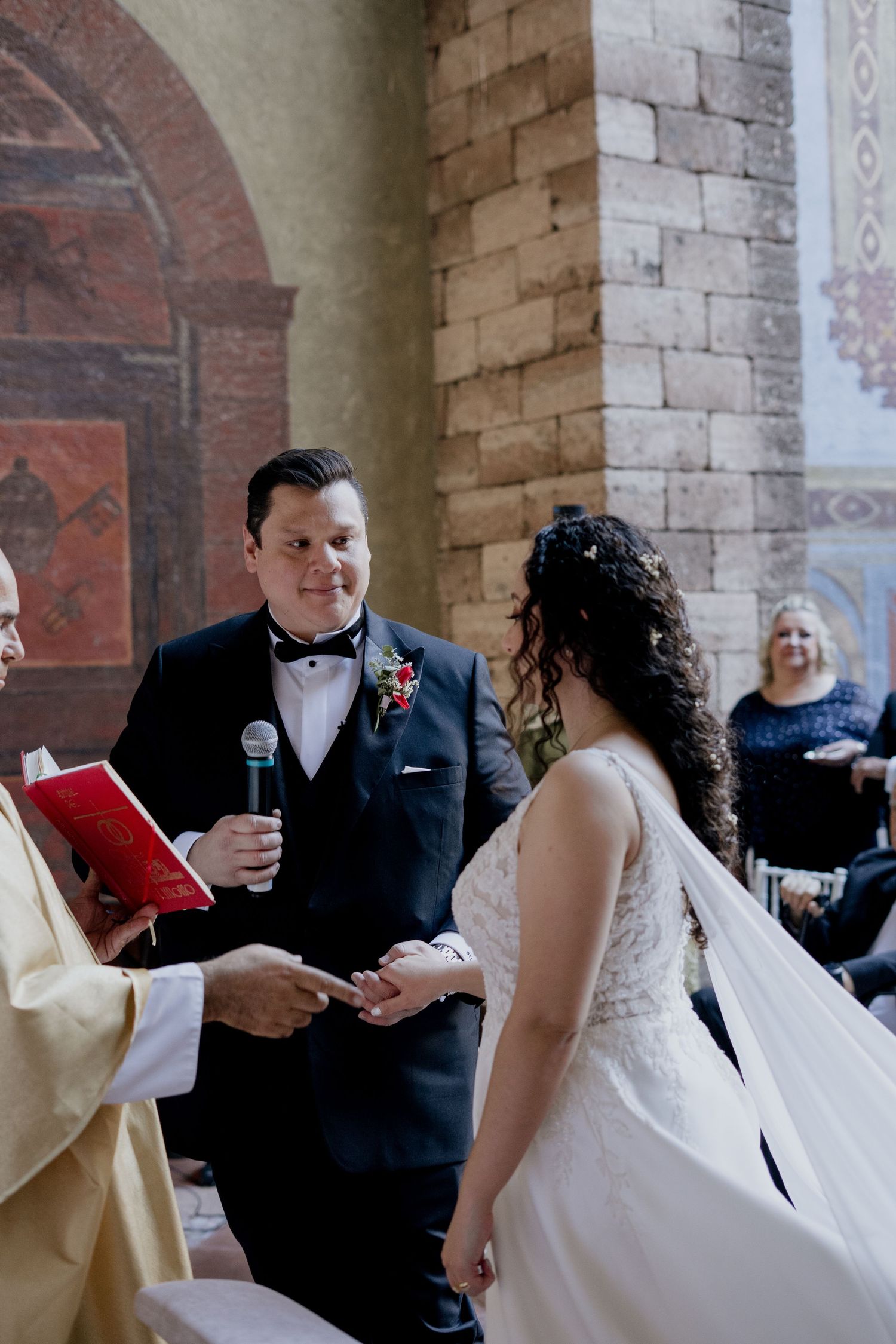 A wedding ceremony in progress inside a historic brick church with arched architecture.