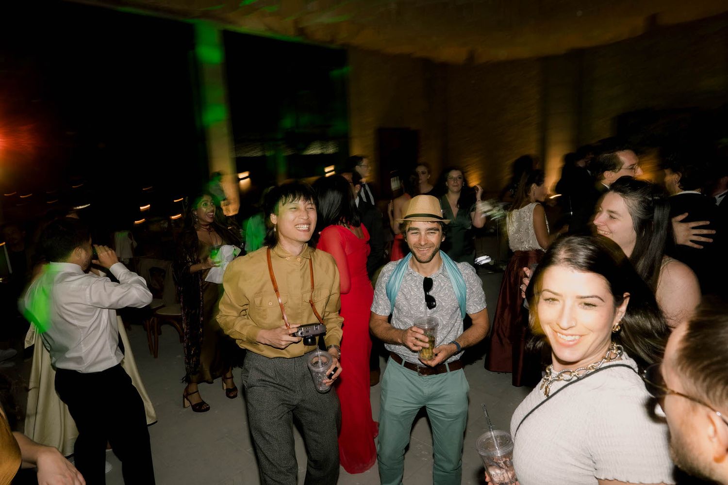 Party guests mingle and dance in casual attire under ambient lighting.
