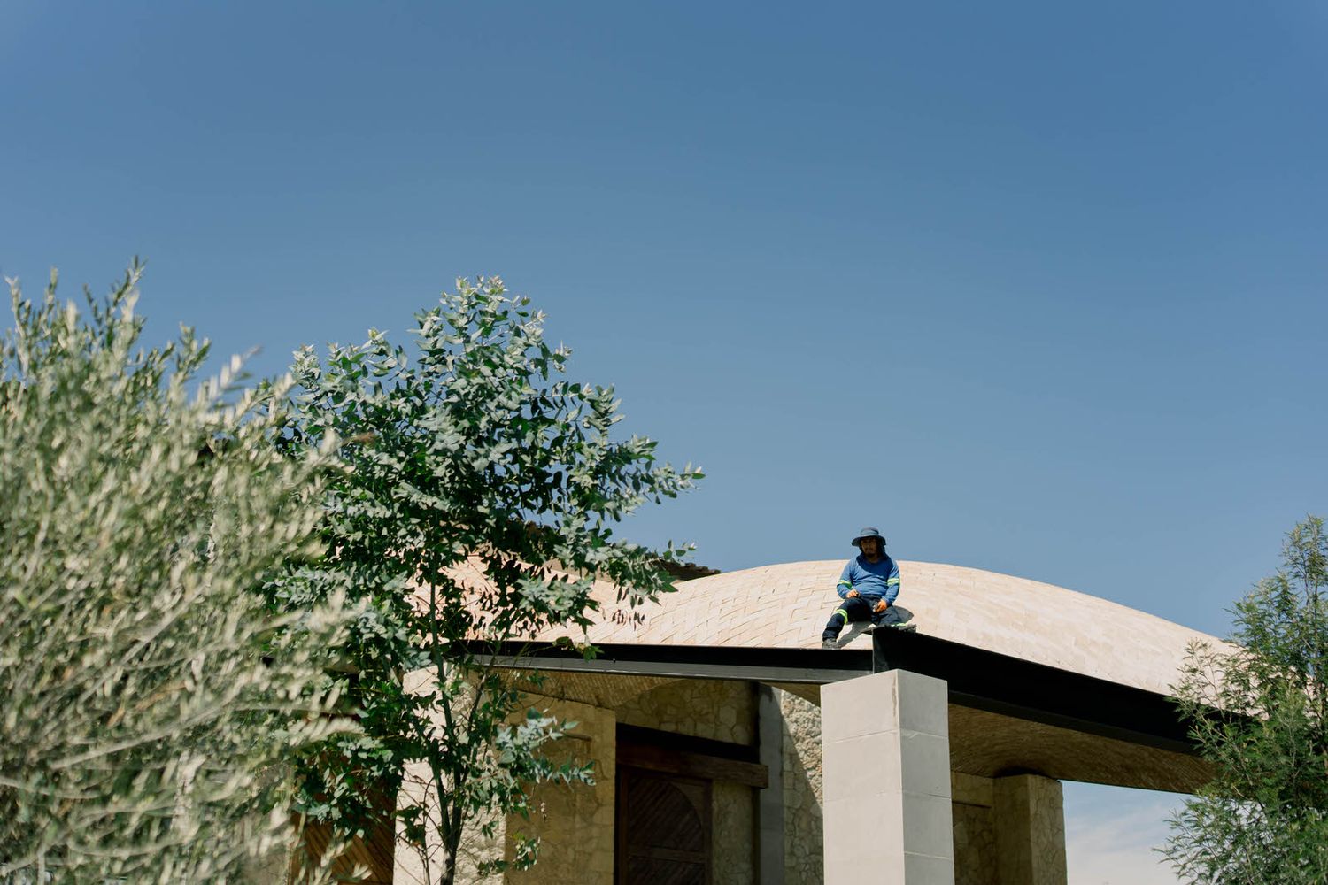 Modern building with flat roof and desert landscaping against bright blue sky.