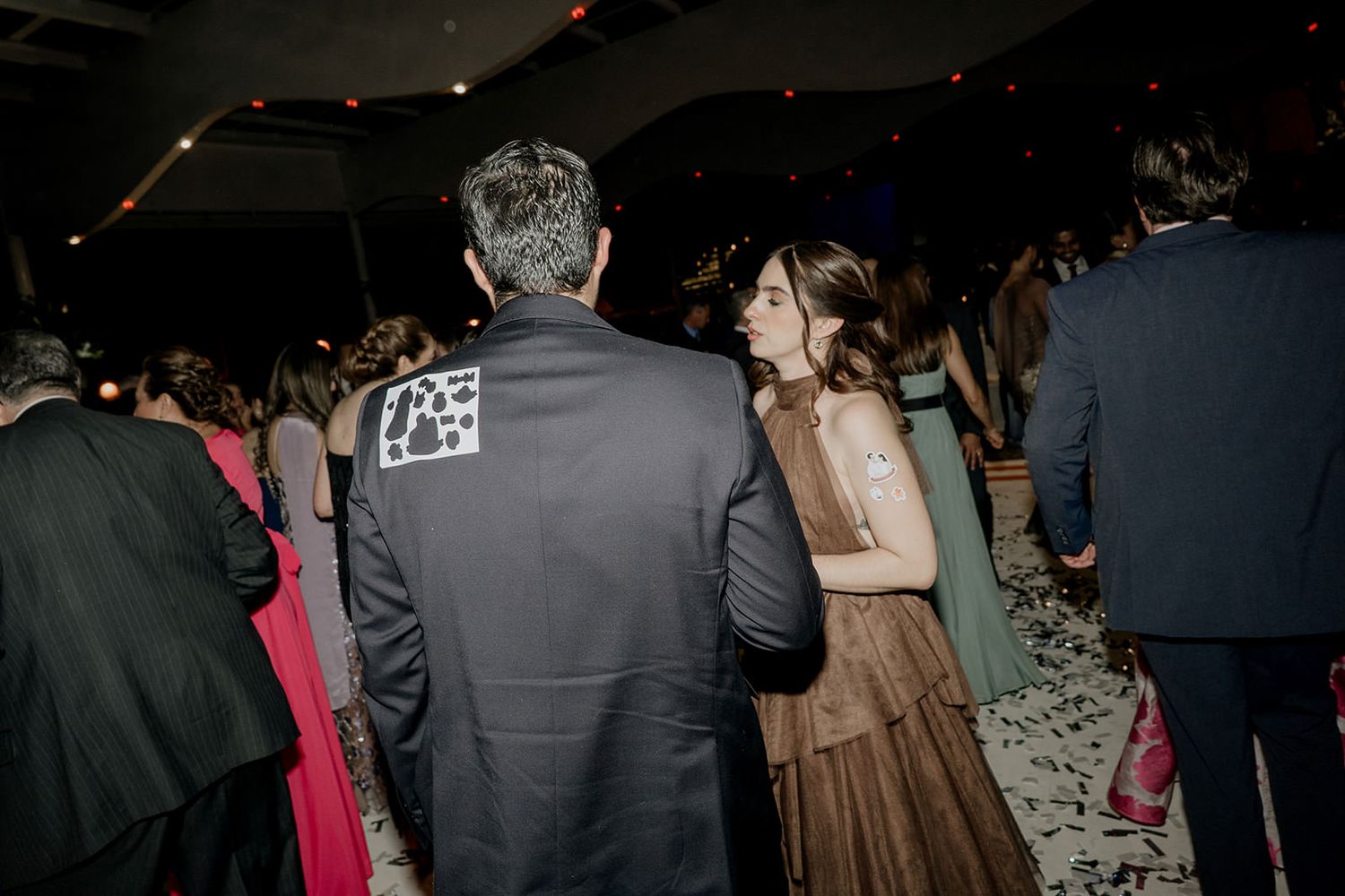 Couple dancing together at evening wedding reception with confetti on the floor.