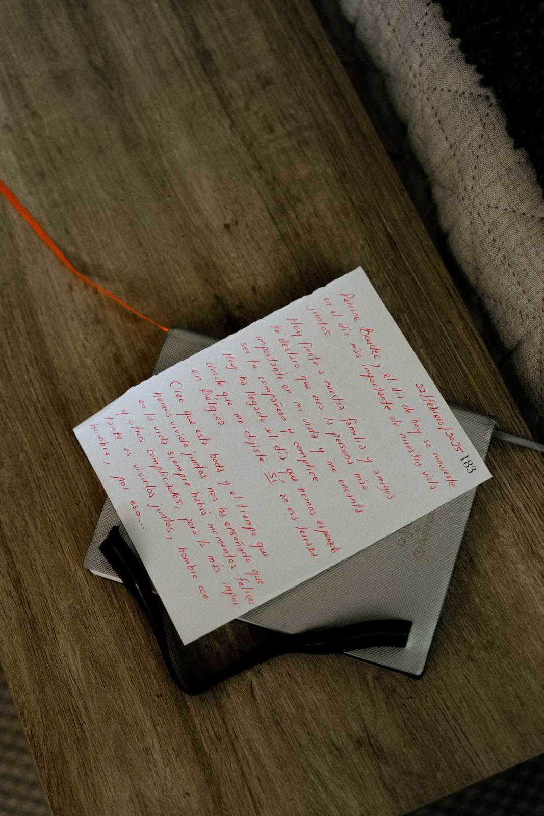 Handwritten note cards with red ink text lying on a dark wooden surface.