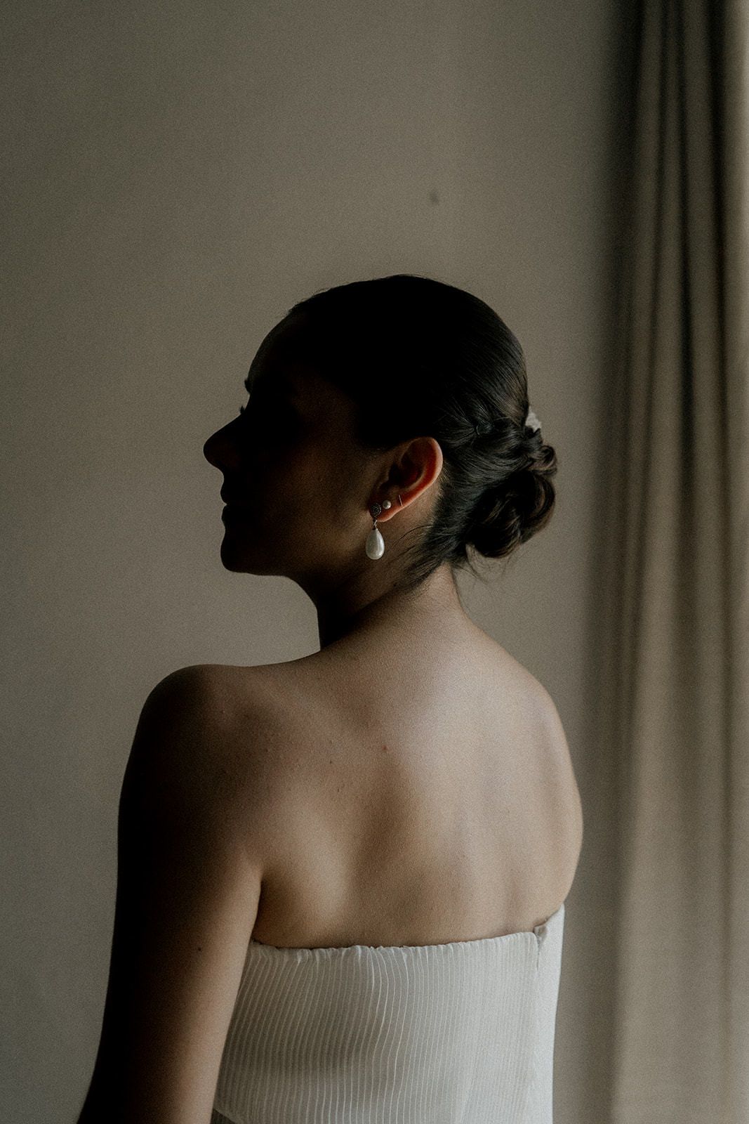 Silhouette shows an elegant updo hairstyle and strapless white dress against a moody backdrop.