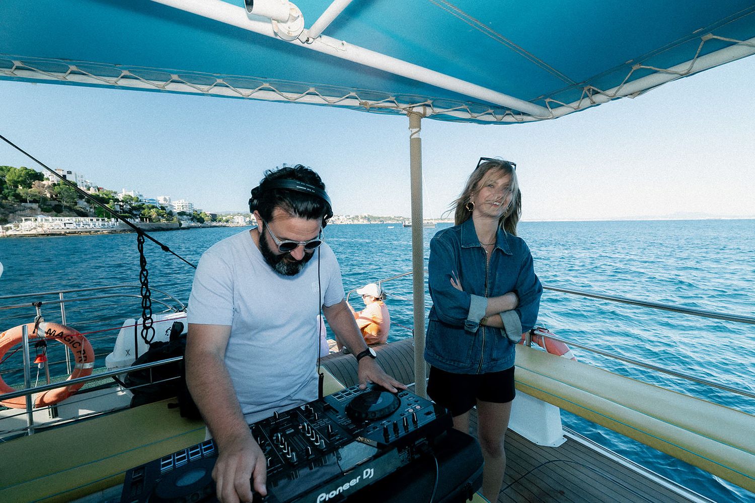 People enjoying a boat trip on turquoise waters with scenic coastal views on a sunny day.