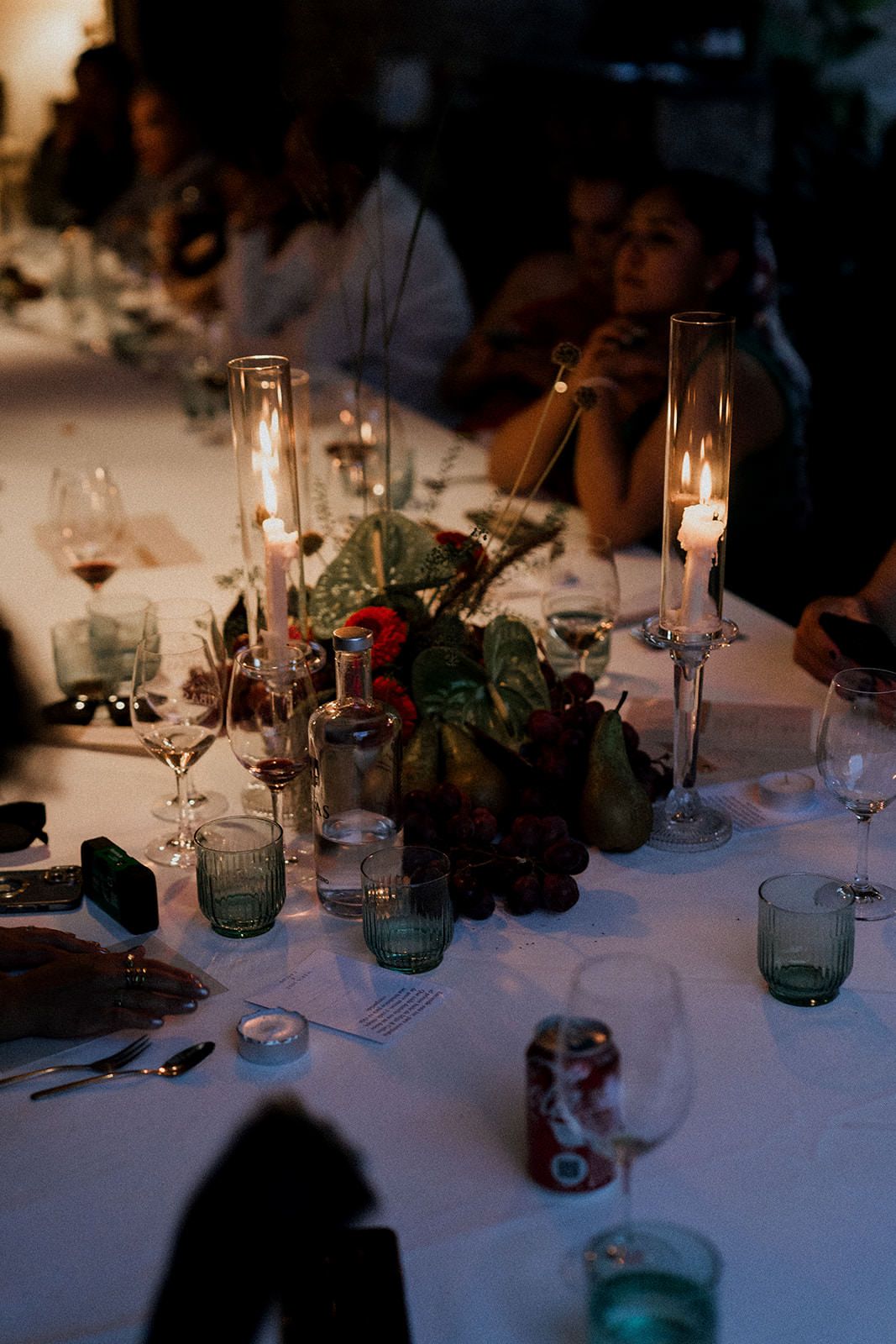 Elegant wedding reception table settings with glowing candles, blue glassware, and white linens in romantic lighting.
