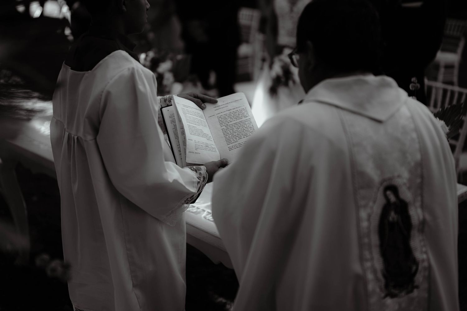 Black and white artistic shot of wedding attendees during an outdoor ceremony.