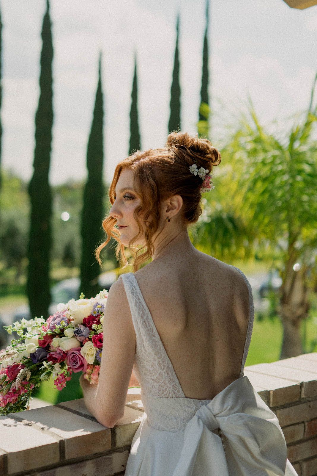 Bridal portrait on terrace with cypress trees and scenic landscape in background.
