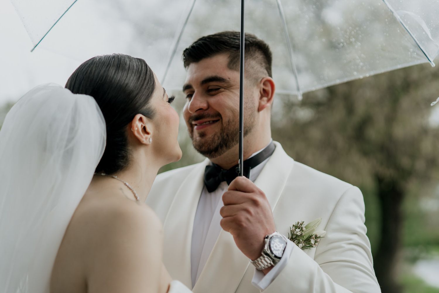 Intimate wedding portraits under a clear umbrella on a rainy day.