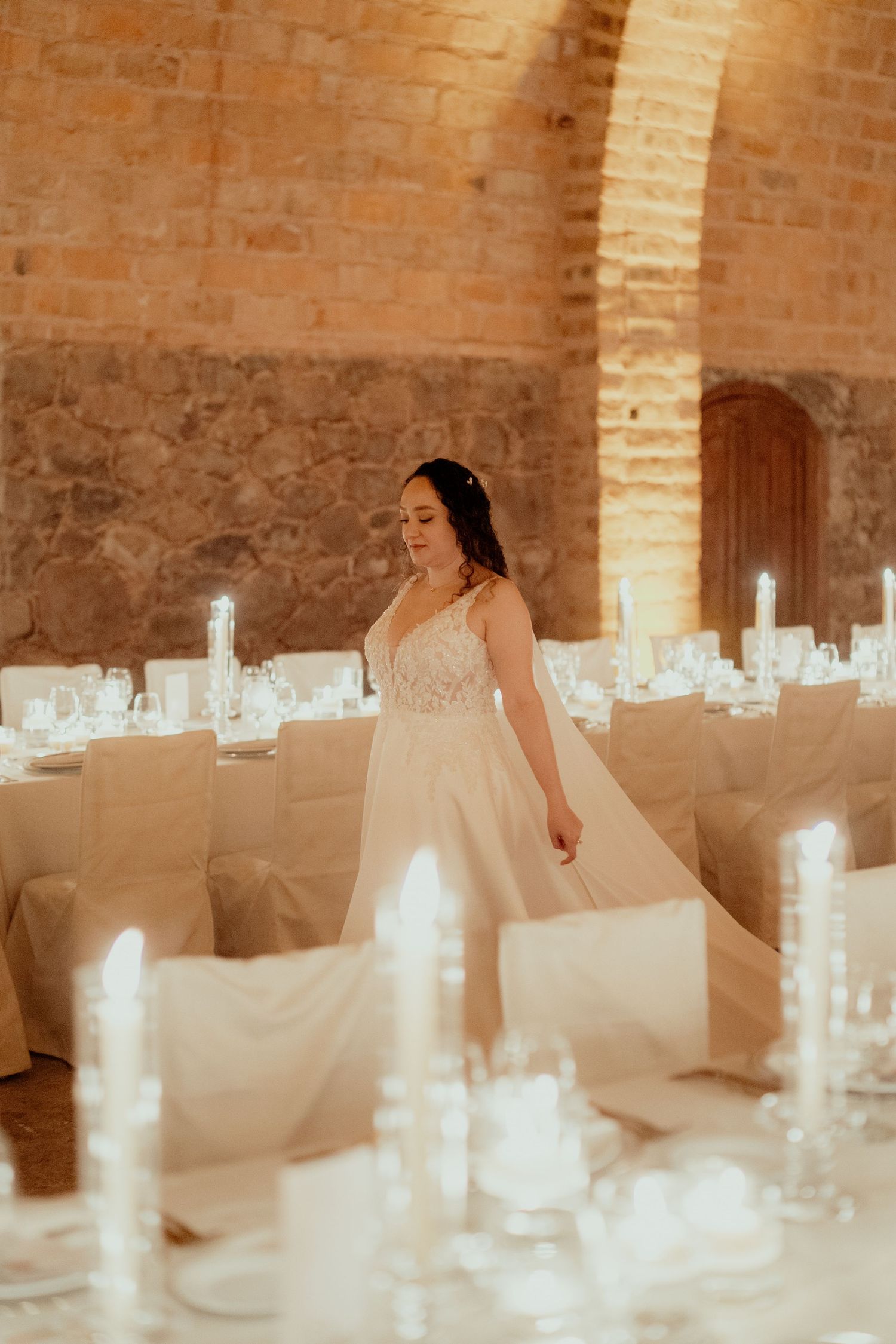 Wedding reception venue with white table settings in a rustic brick vault.
