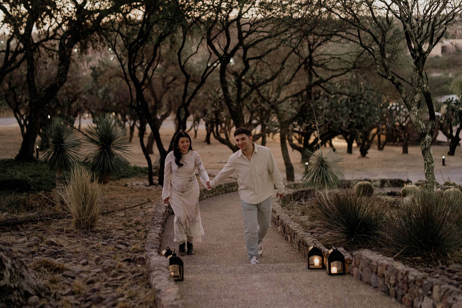 A romantic proposal scene at sunset with lanterns glowing in the background.