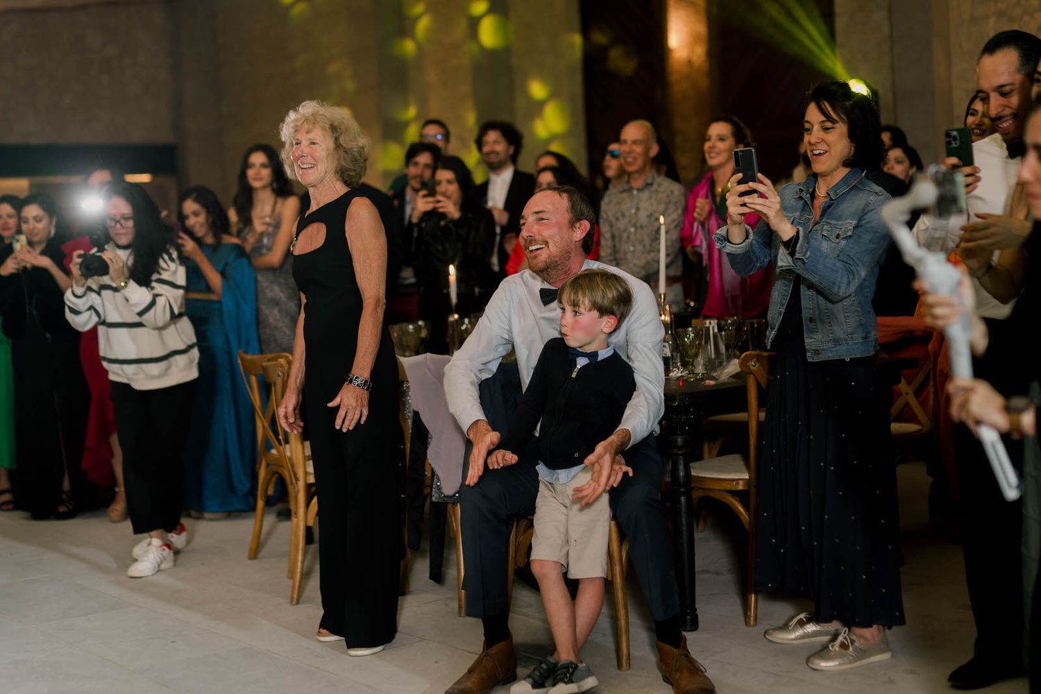 Wedding guests gather around the dance floor watching the celebration unfold.