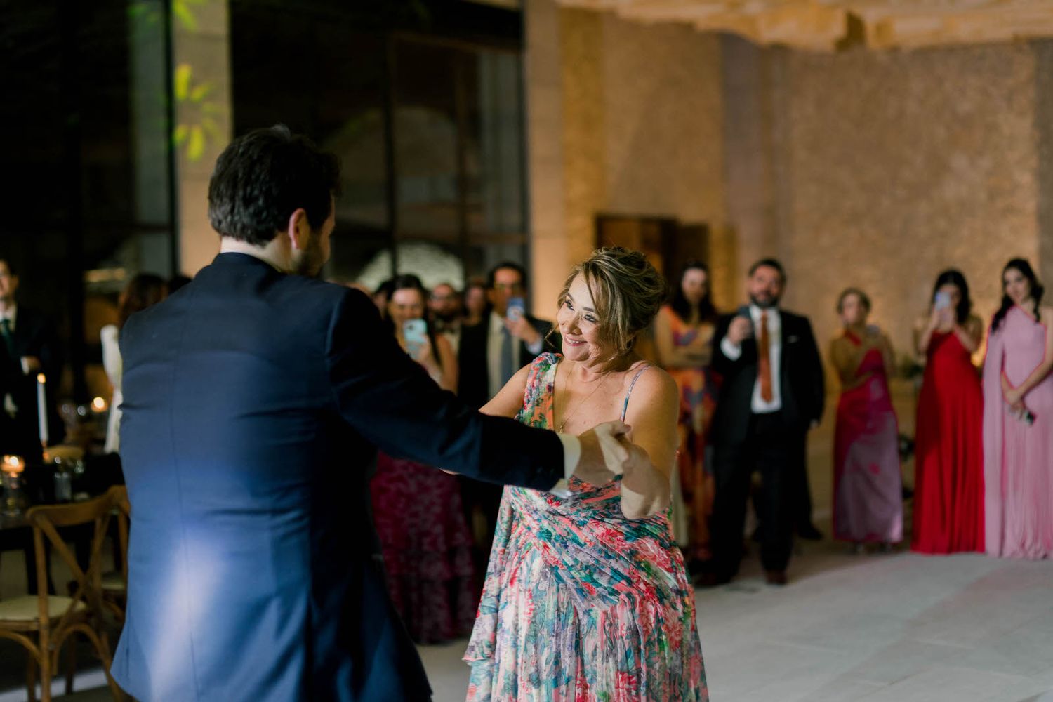 Wedding reception guests in formal attire stand along the edges of a spacious ballroom.
