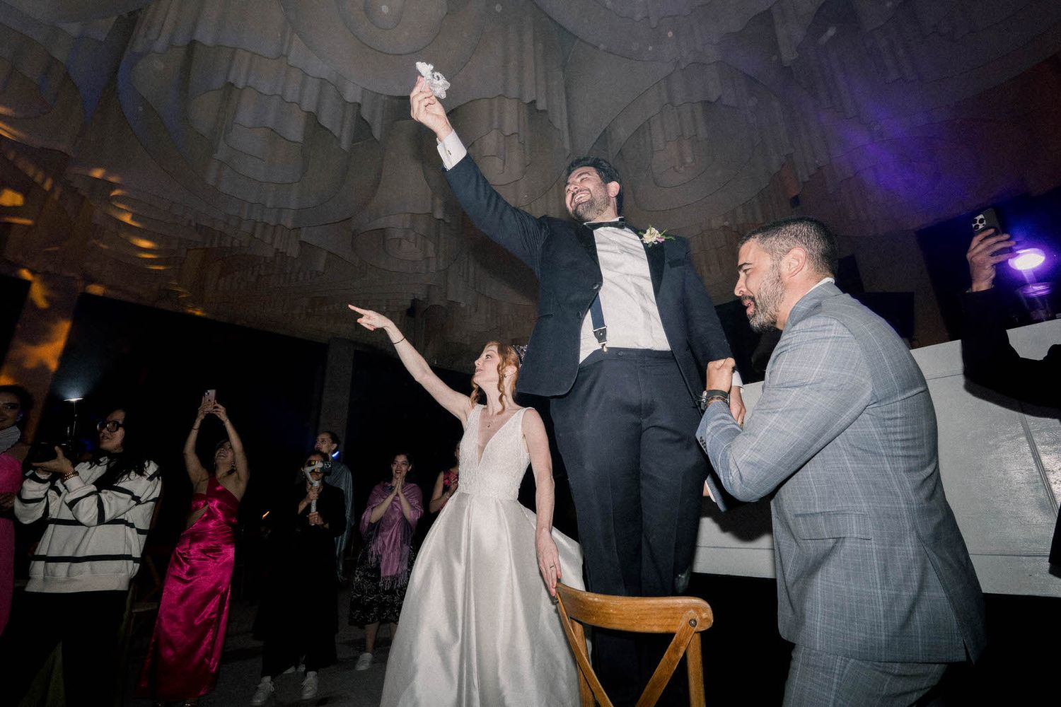 Wedding celebration reaches peak excitement as guests cheer during a reception moment.