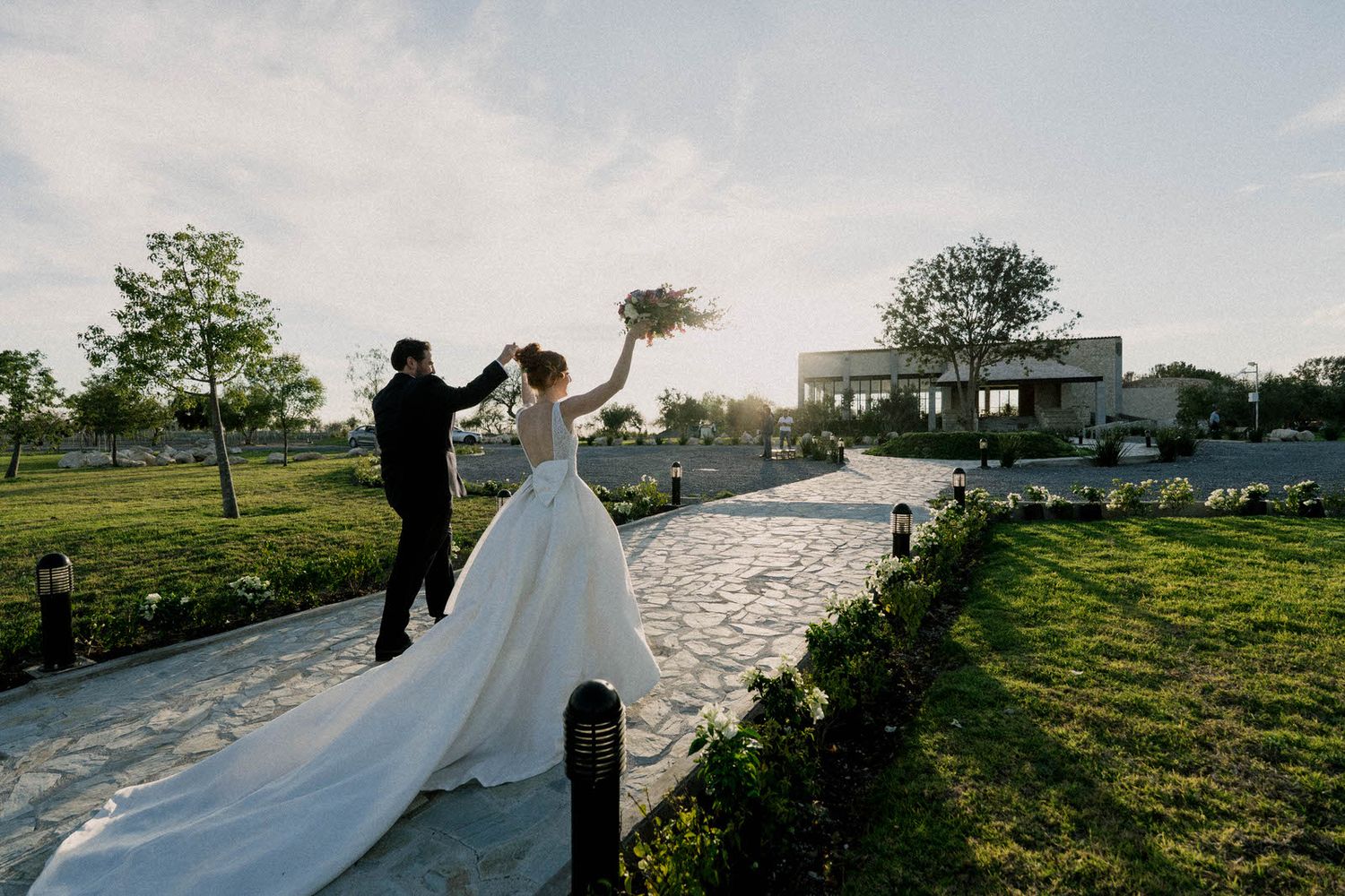 Scenic outdoor wedding ceremony setup with white chairs and floral arrangements at sunset.
