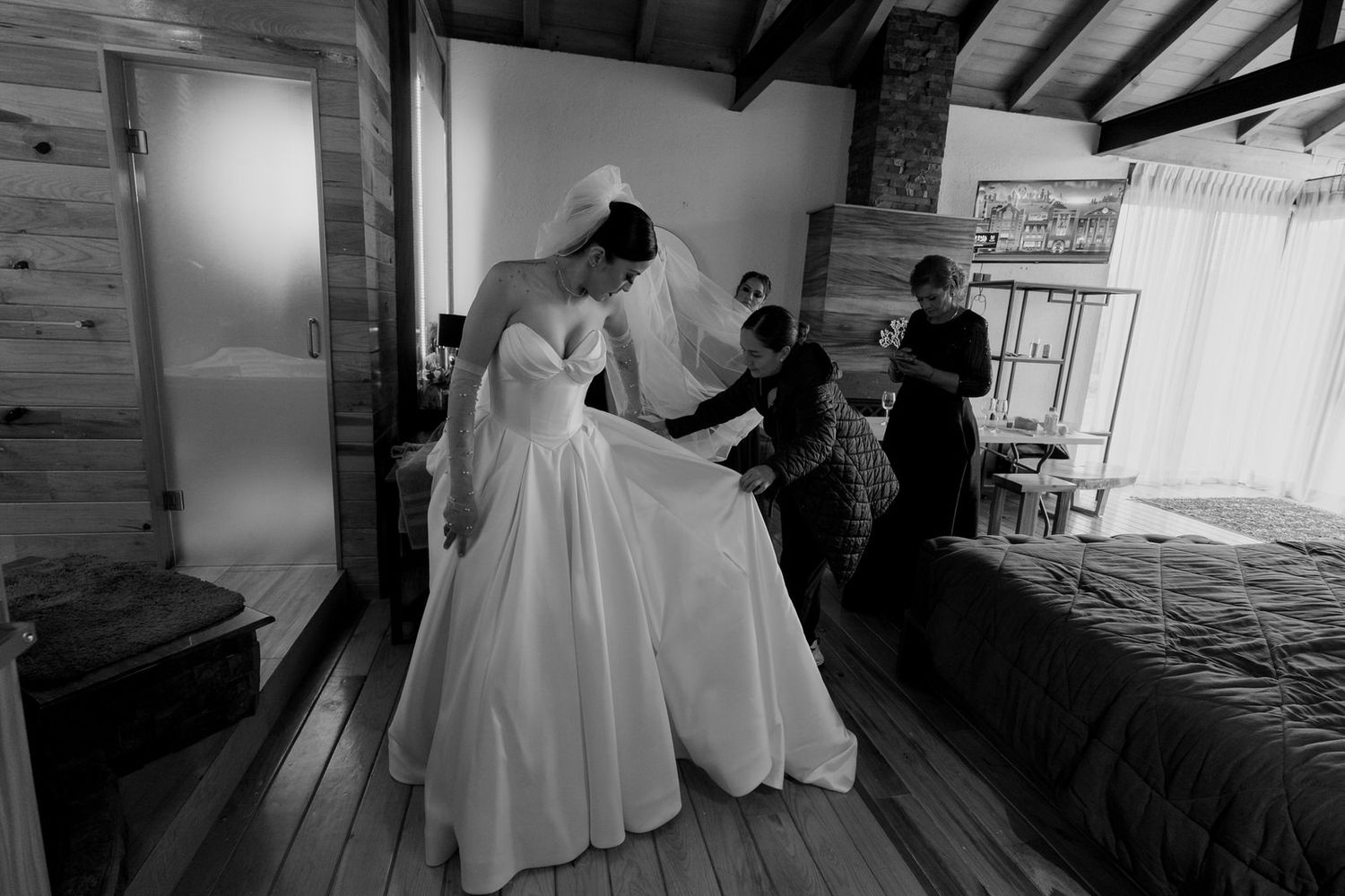 Black and white photo of wedding preparation in a rustic wooden interior.