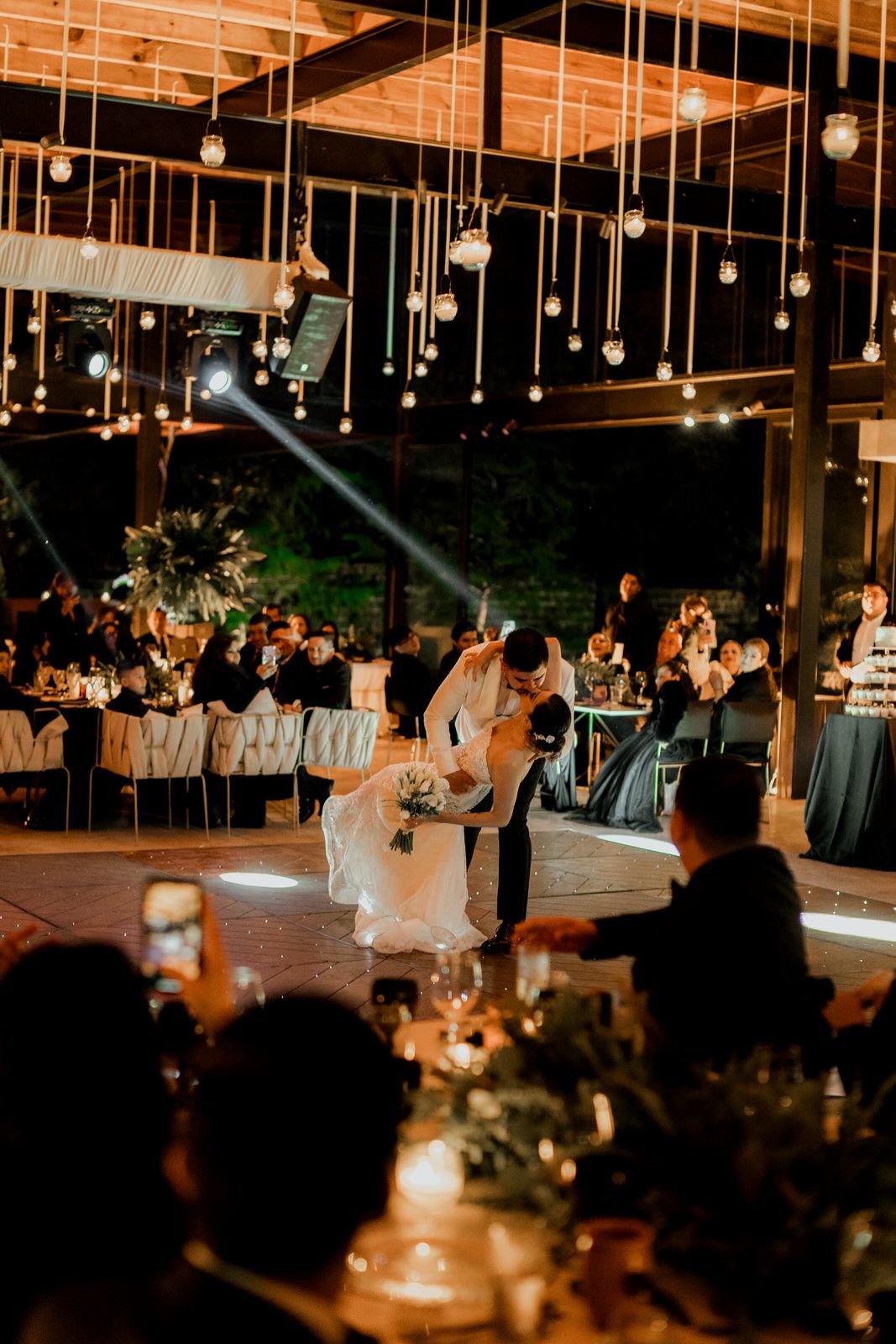 Wedding reception celebration under warm lighting with guests dancing.