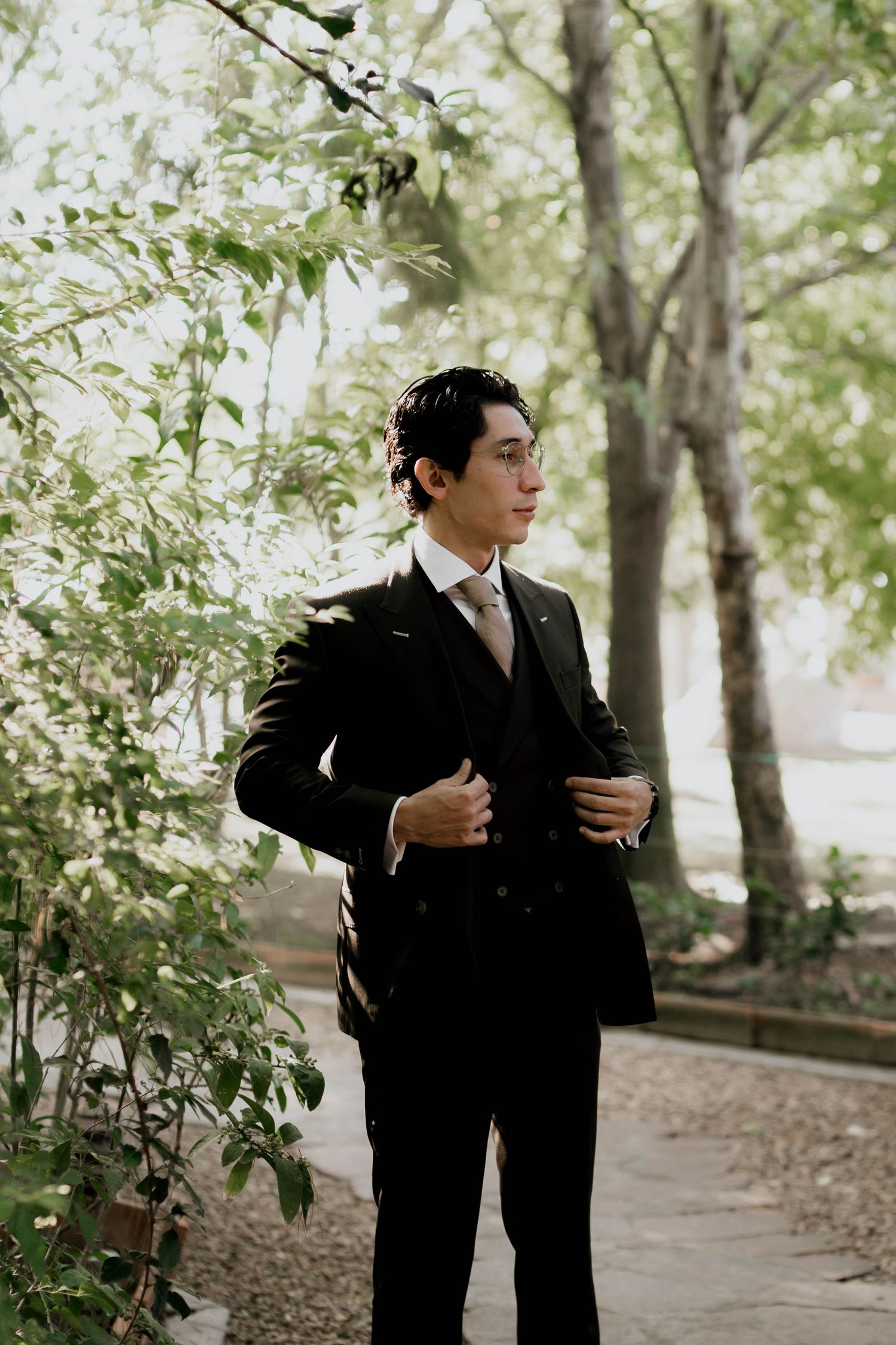 Formal attire photoshoot in a natural outdoor setting with trees and filtered sunlight.