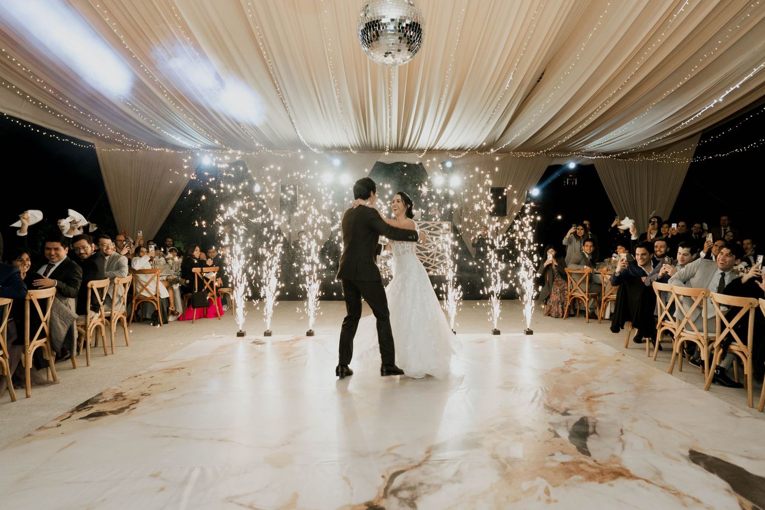 Indoor wedding venue with white draped ceiling and dramatic lighting effects during a dance performance.