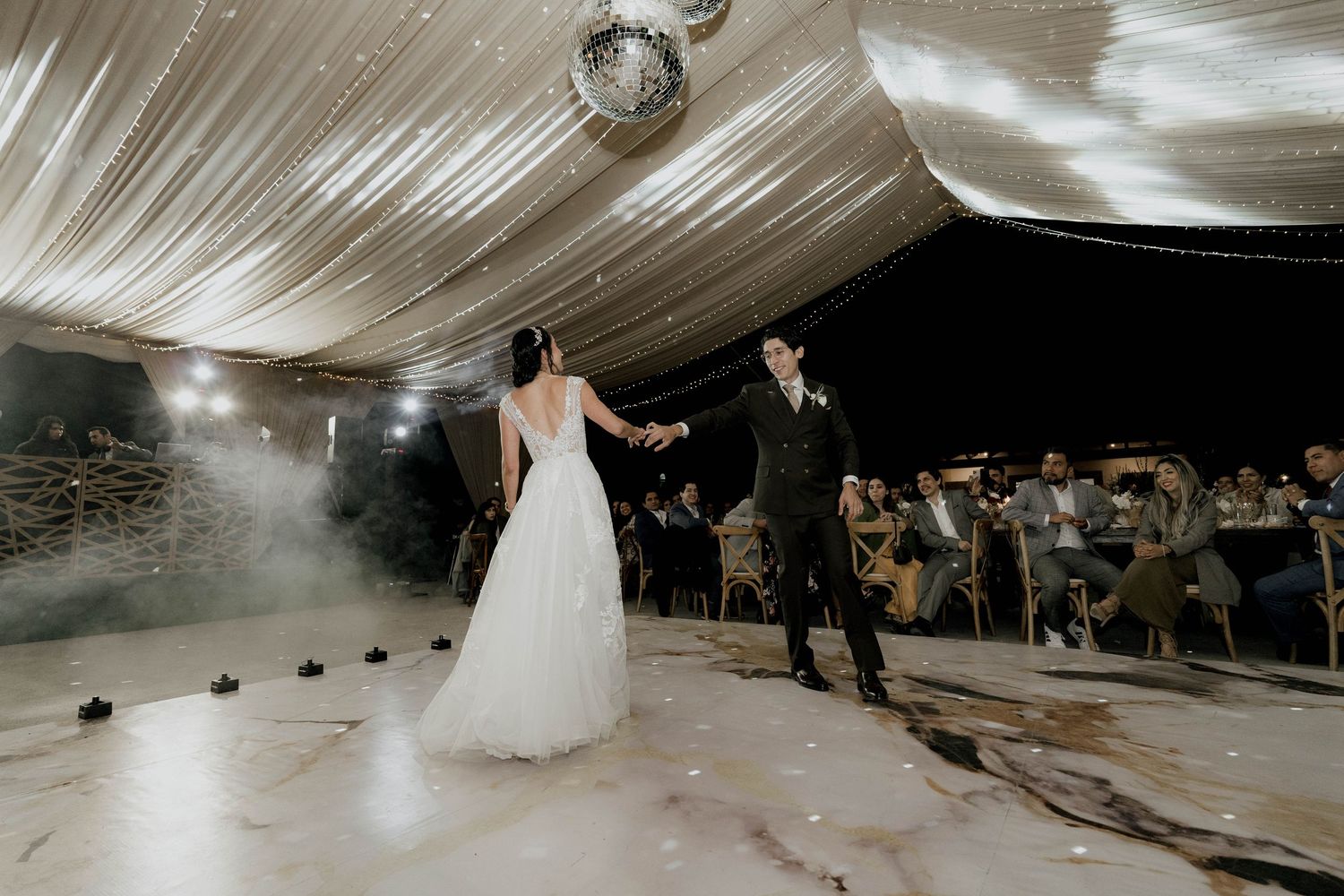 Wedding celebration with dramatic indoor pyrotechnic effects lighting up a draped tent venue.