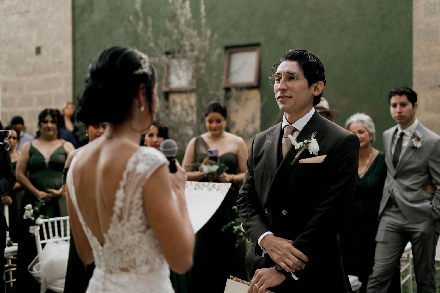 Wedding party celebrates against rustic stone wall backdrop.
