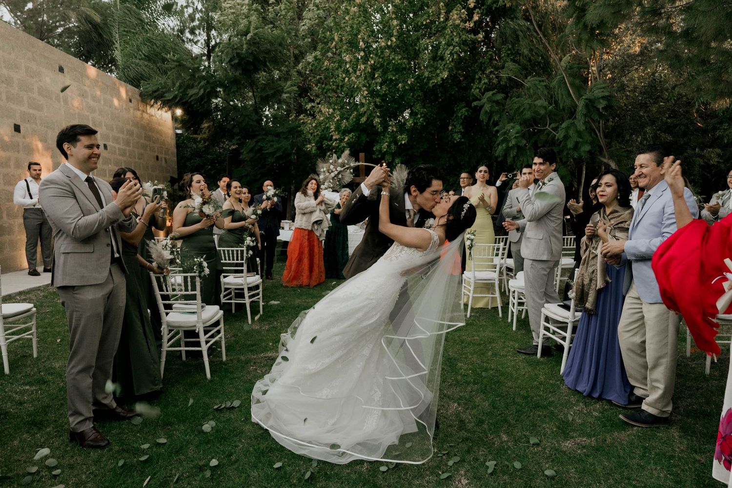 Wedding party and guests celebrating at an elegant outdoor garden reception.