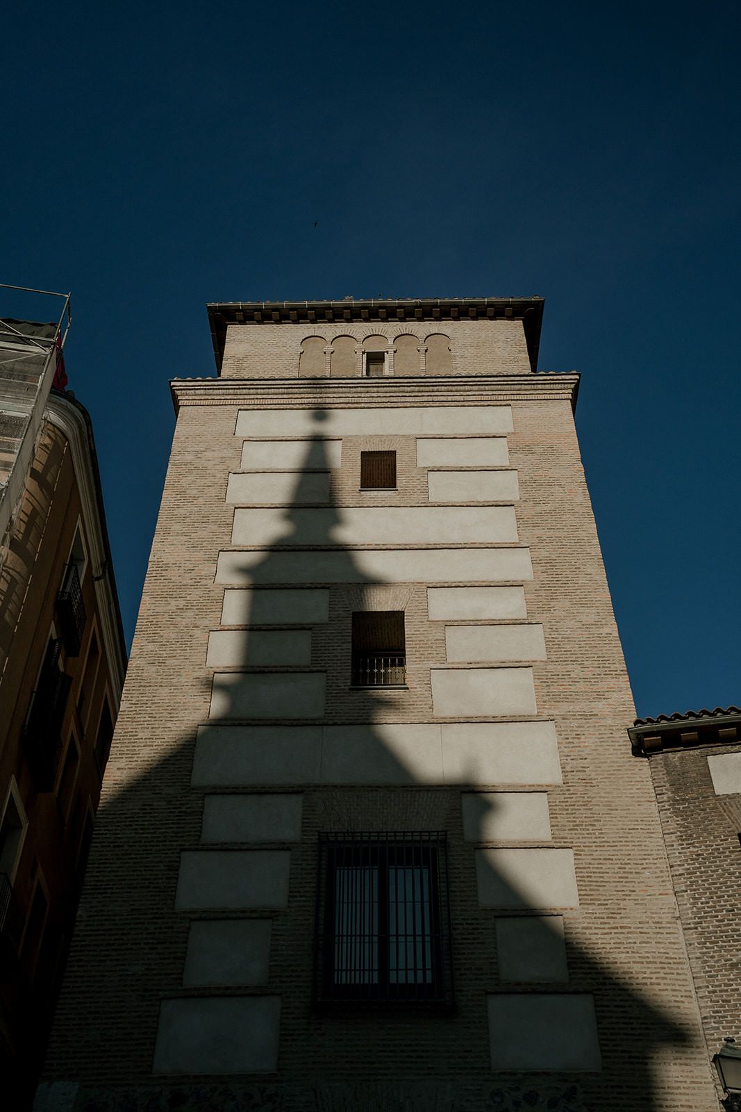 A sequence of photos showing a shadow progressively moving across a beige building facade with white windows.