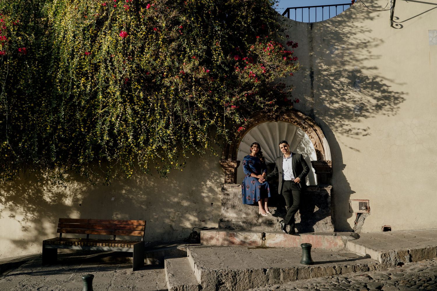Historic stone wall with climbing vines and colonial architecture in background.