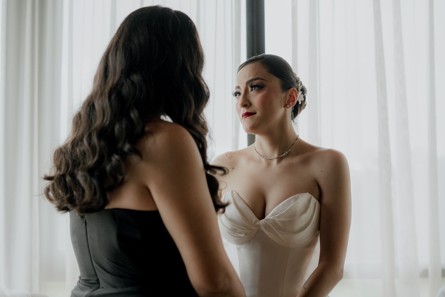 A quiet conversation during wedding preparations near bright windows.