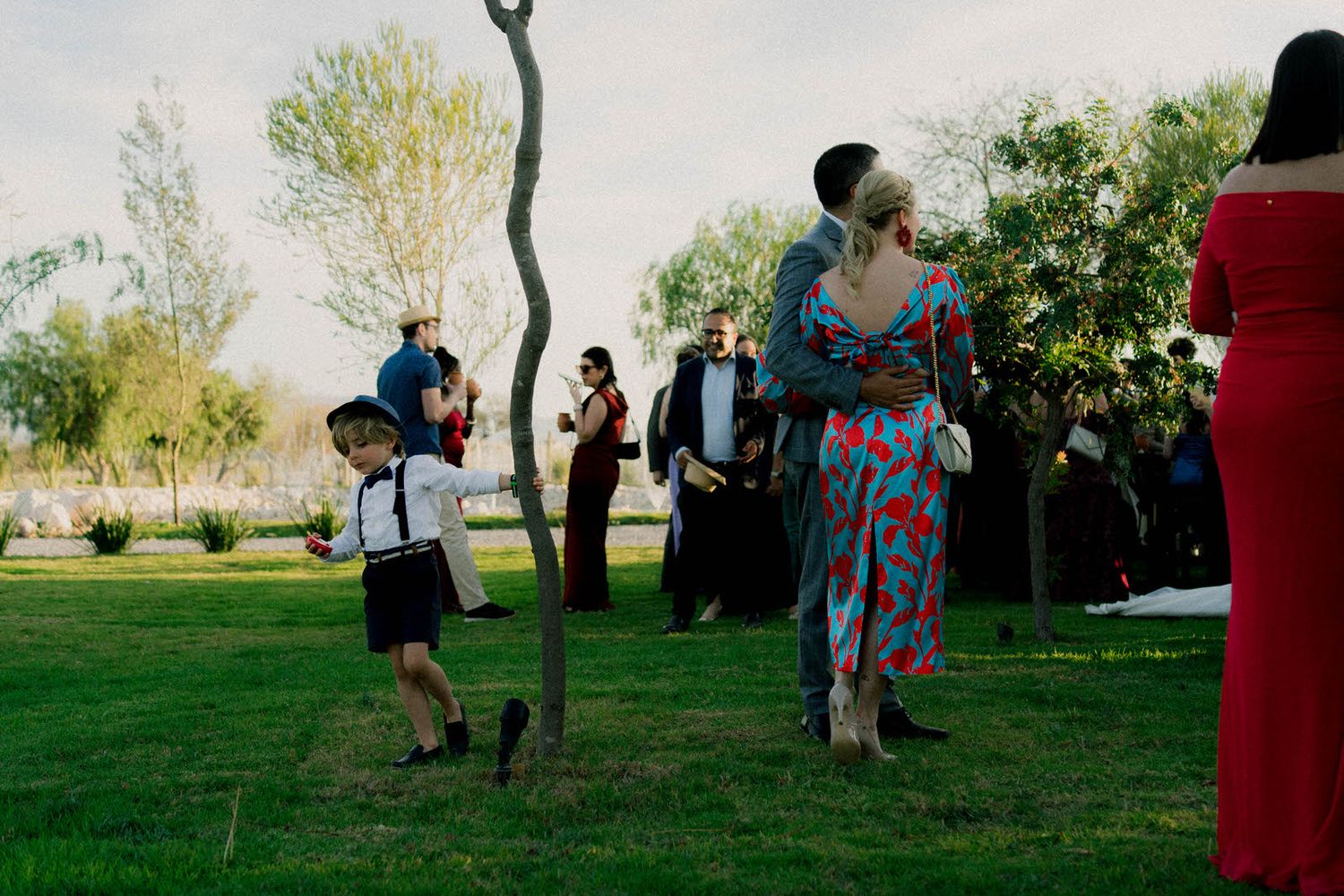 Wedding celebration on a grassy lawn with decorative red pillars.