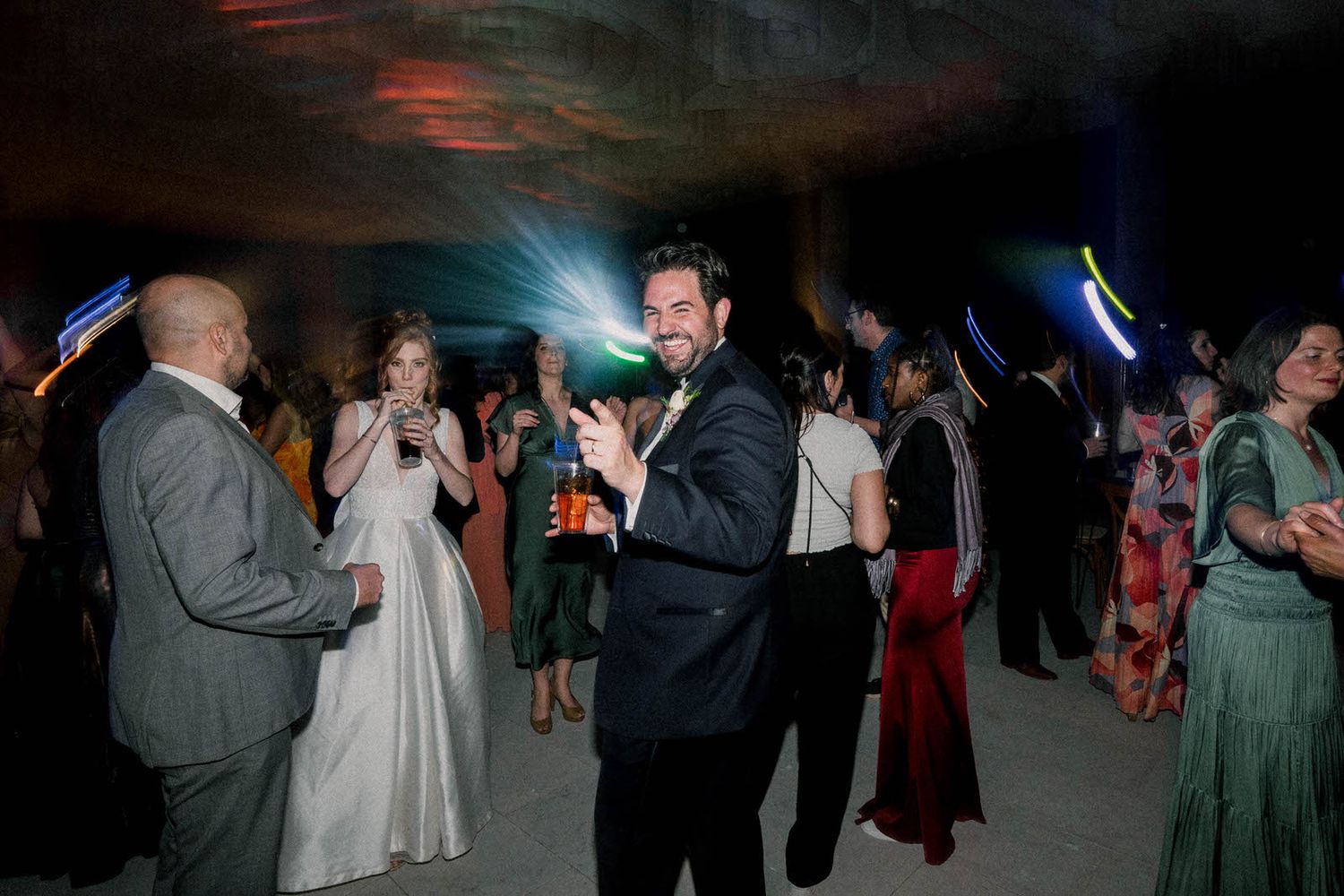 Guests dancing and celebrating at an elegant evening reception with atmospheric lighting.
