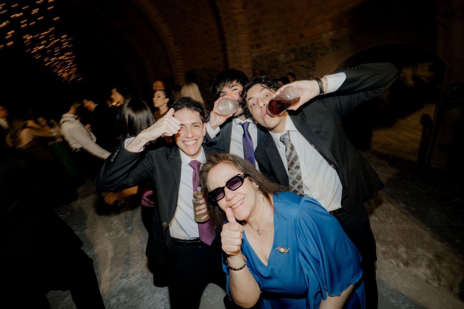 Wedding guests pose playfully for a group photo during the reception celebration.