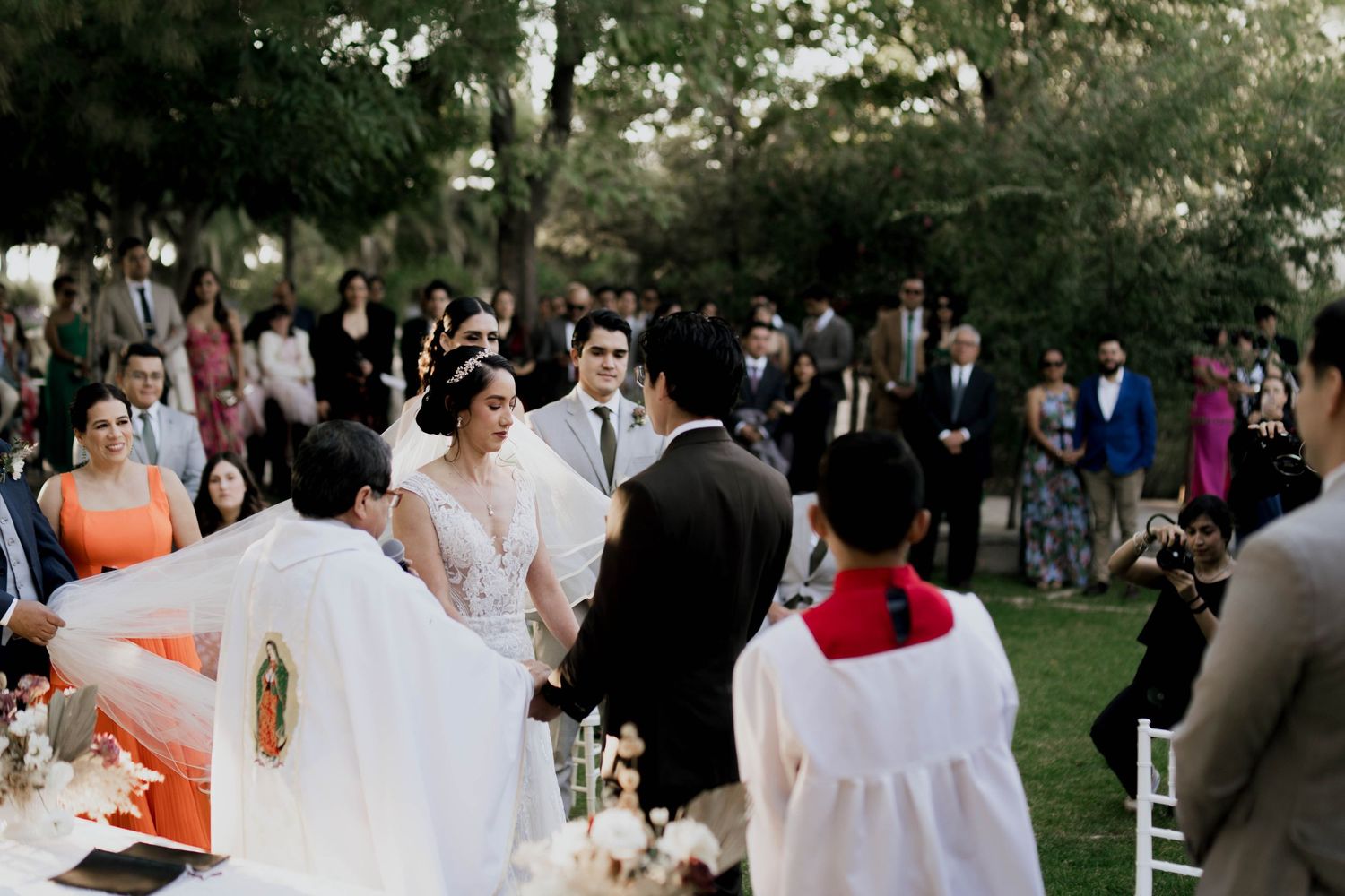 Outdoor wedding reception with guests mingling among white chairs and decorations.