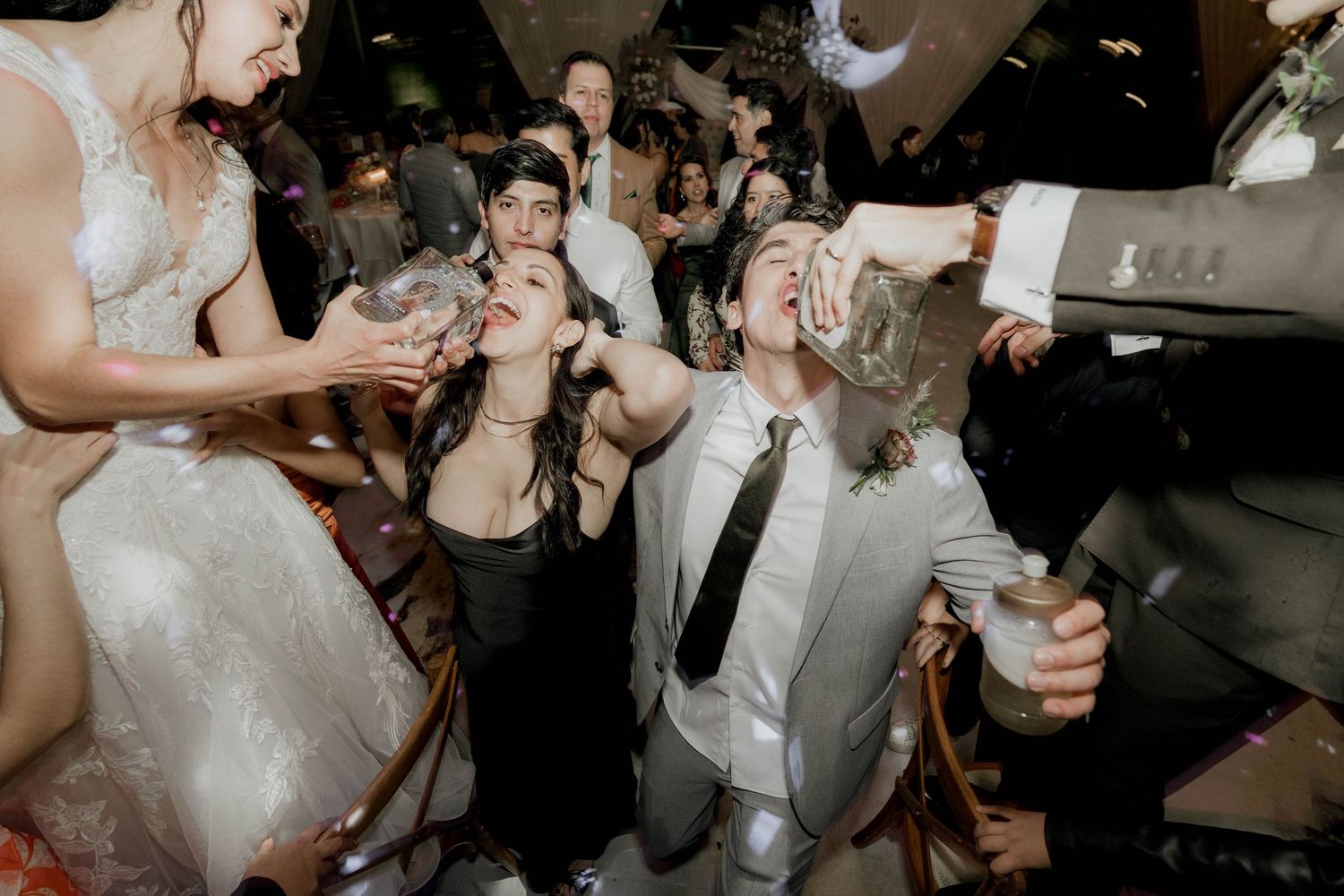 Celebratory moment with guests singing and dancing at a lively wedding reception.