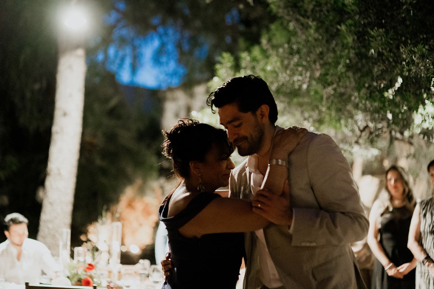 A romantic dance under moonlit trees at an outdoor evening celebration.