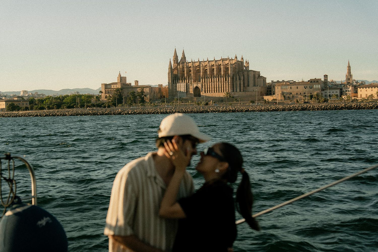 Panoramic sequence showing a sailboat sailing across choppy waters with a historic European cathedral visible on the shoreline.
