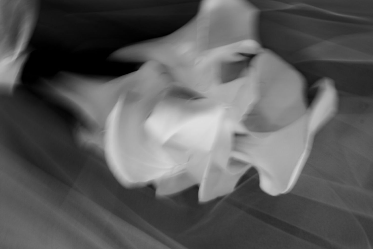 Abstract black and white motion blur photograph of a dancer in flowing white costume captured mid-movement.