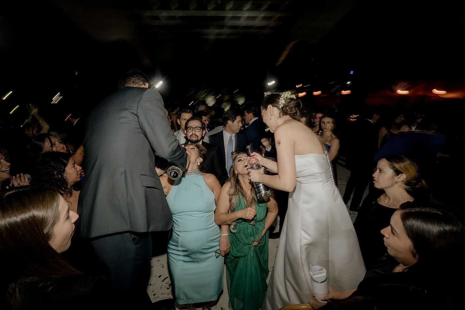 Bride and groom interact with guests on the dance floor during a lively wedding reception celebration.