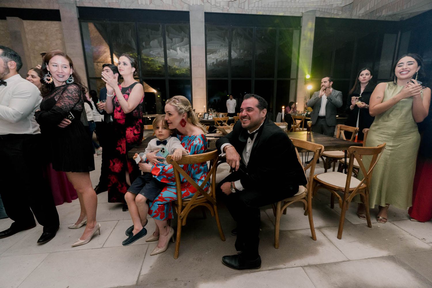 Wedding guests seated at tables around a dance floor during an evening reception.