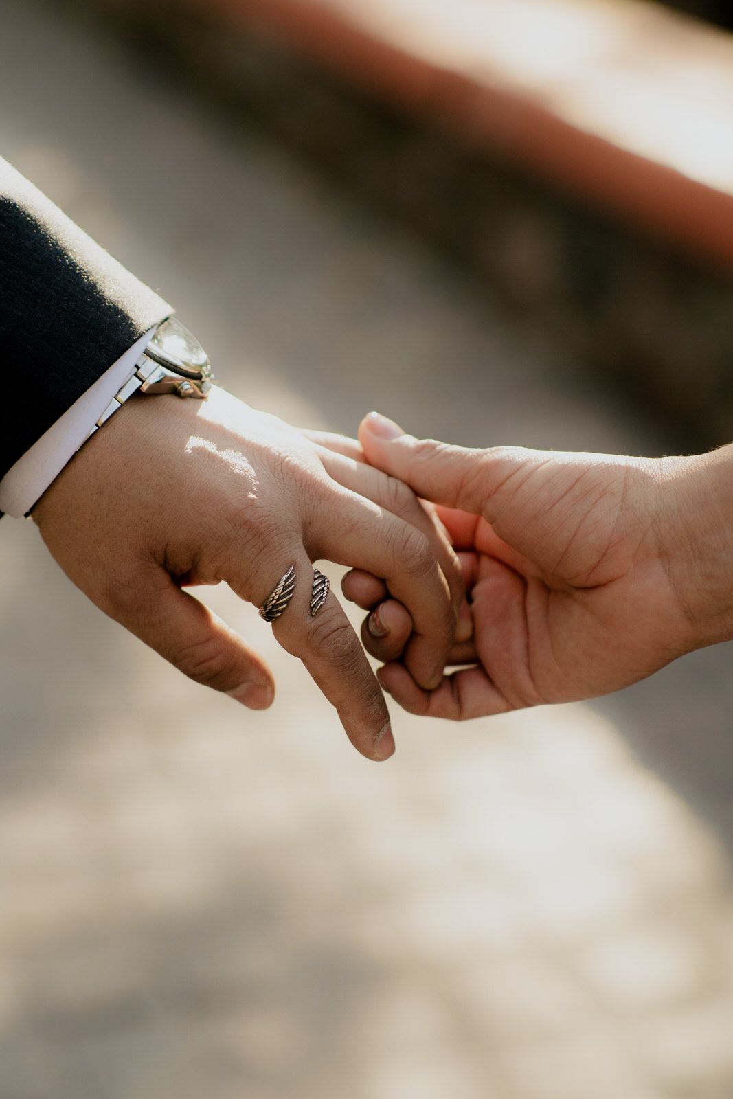 Close-up of hands touching with engagement ring visible in natural lighting.