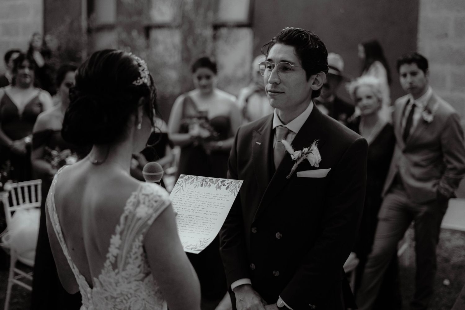 Black and white photo of wedding guests seated during an outdoor ceremony.