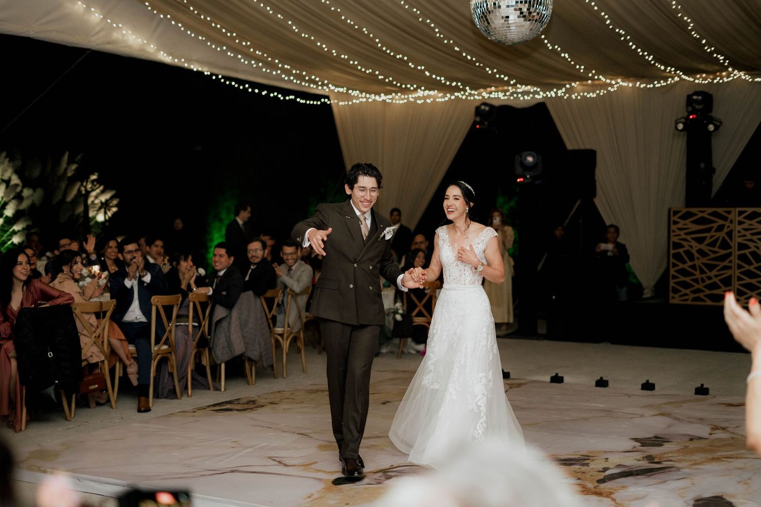 Wedding reception dance floor scene with elegant white draping and dramatic lighting effects.