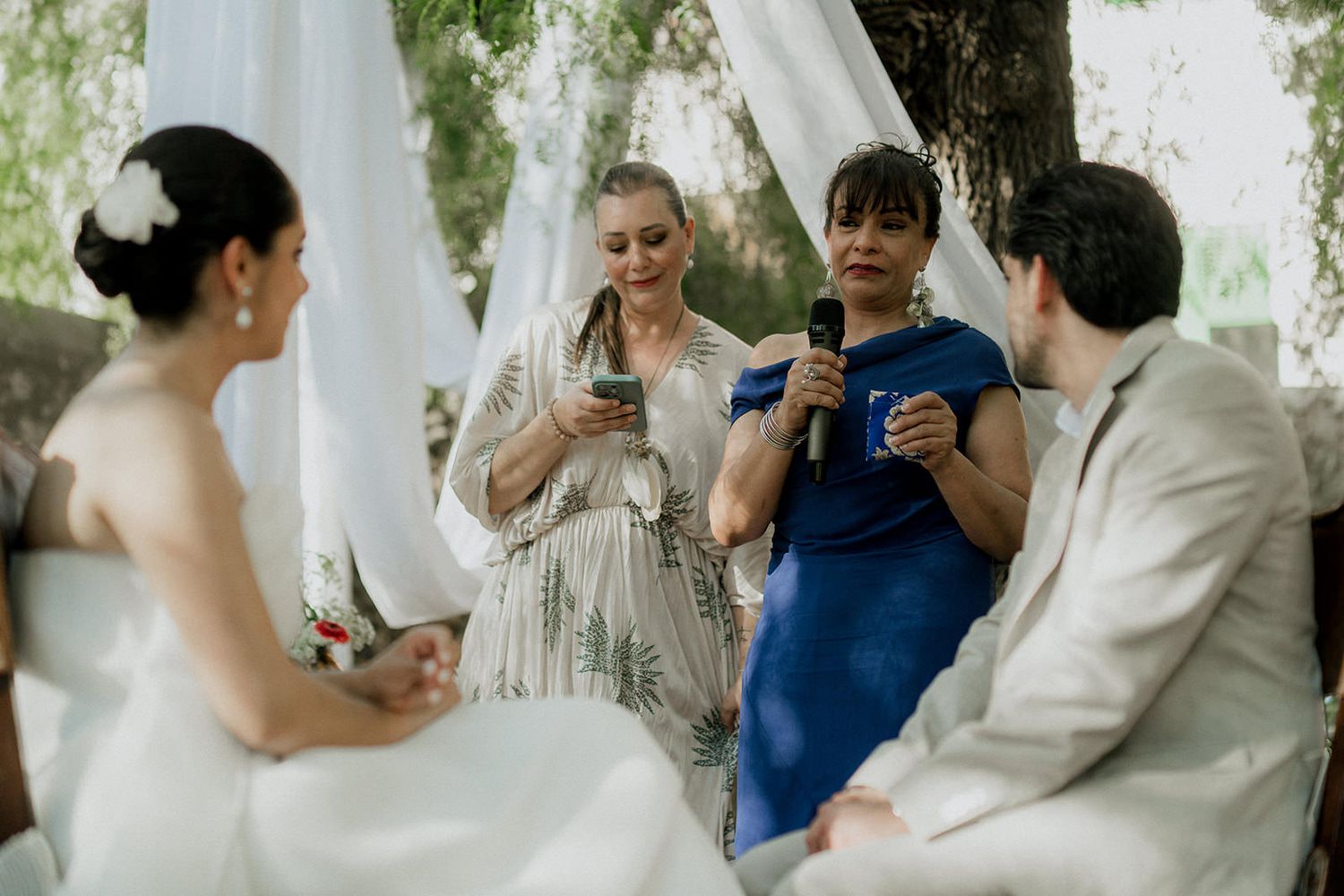Guests gather around for a celebratory moment at an outdoor wedding reception.