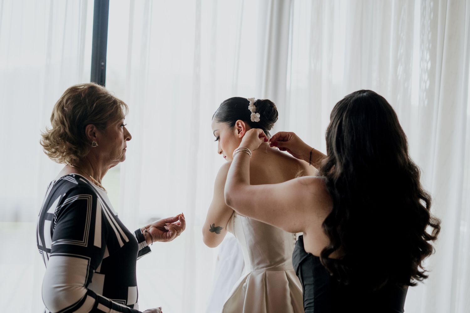 Wedding preparation scene with multiple people helping with final touches.